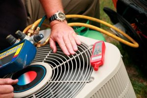 technician's hand on top of outdoor ac unit, with tools on top for testing