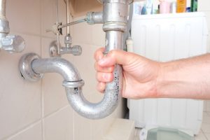 hand gripping p-trap pipe underneath sink