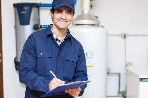 smiling-technician-holding-clipboard-and-standing-in-front-of-water-heater