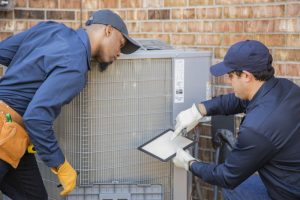 two-technicians-looking-over-checklist-as-they-service-air-conditioner