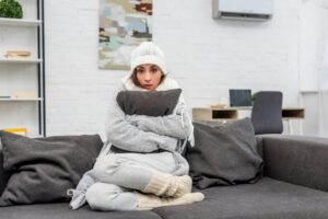 woman-huddled-on-couch-in-winter-clothes