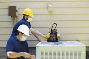 two-technicians-working-on-air-conditioner-outside-unit