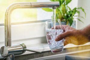 hand-holding-glass-of-water-being-filled-at-sink